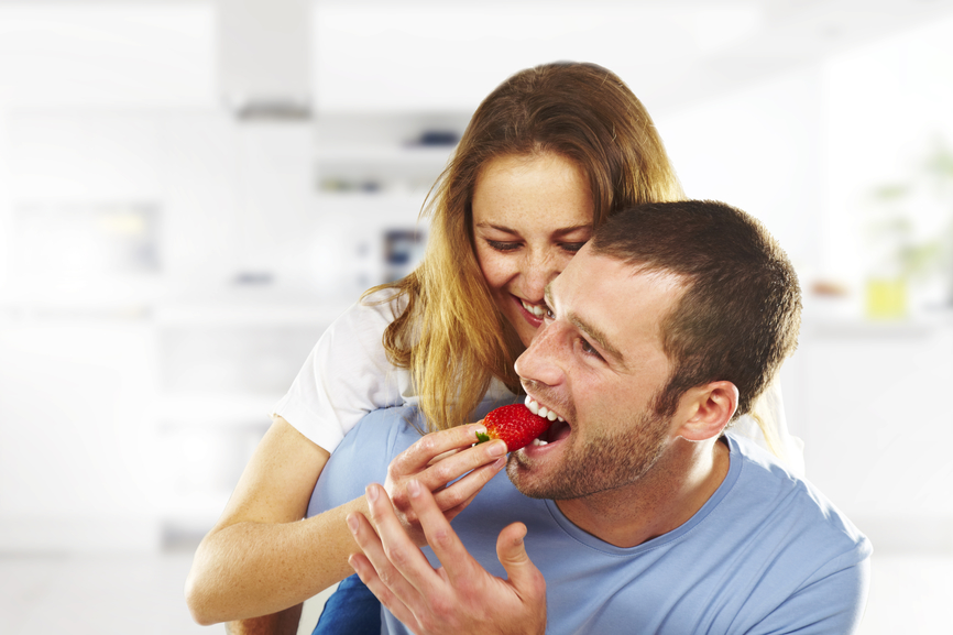 Девушка кормит мужчину клубникой