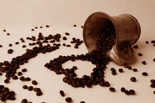 Рассыпанные из чашки зёрна кофе сложены в виде сердца