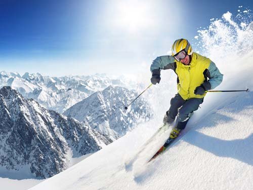 Мужчина на лыжах скатывается с горы, счастлив