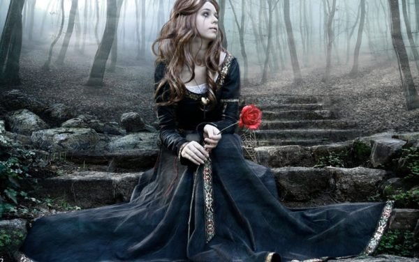 Девушка с розой в руках сидит на ступенях каменной лестницы